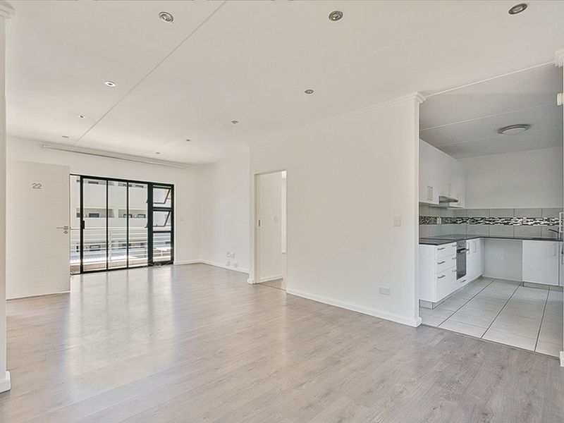 Spacious open-plan living area featuring laminate flooring, recessed lighting, and a modern kitchen with built-in appliances and tiled backsplash.