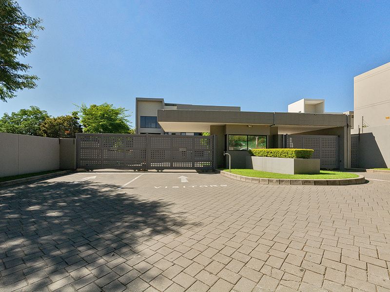 The secure entrance to the apartment complex features a paved visitor parking area, automated security gates, and a dedicated guard house.