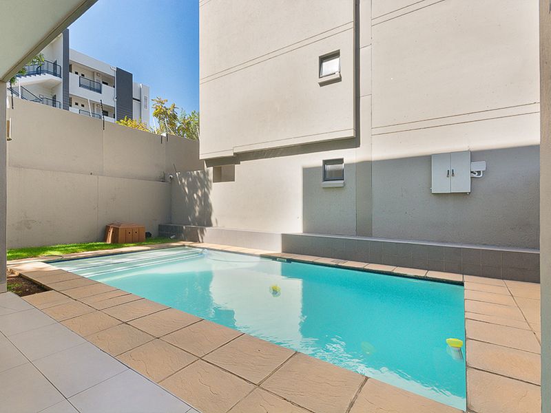 A private outdoor swimming pool area featuring a tiled surround and high boundary walls, providing a secluded space for relaxation.