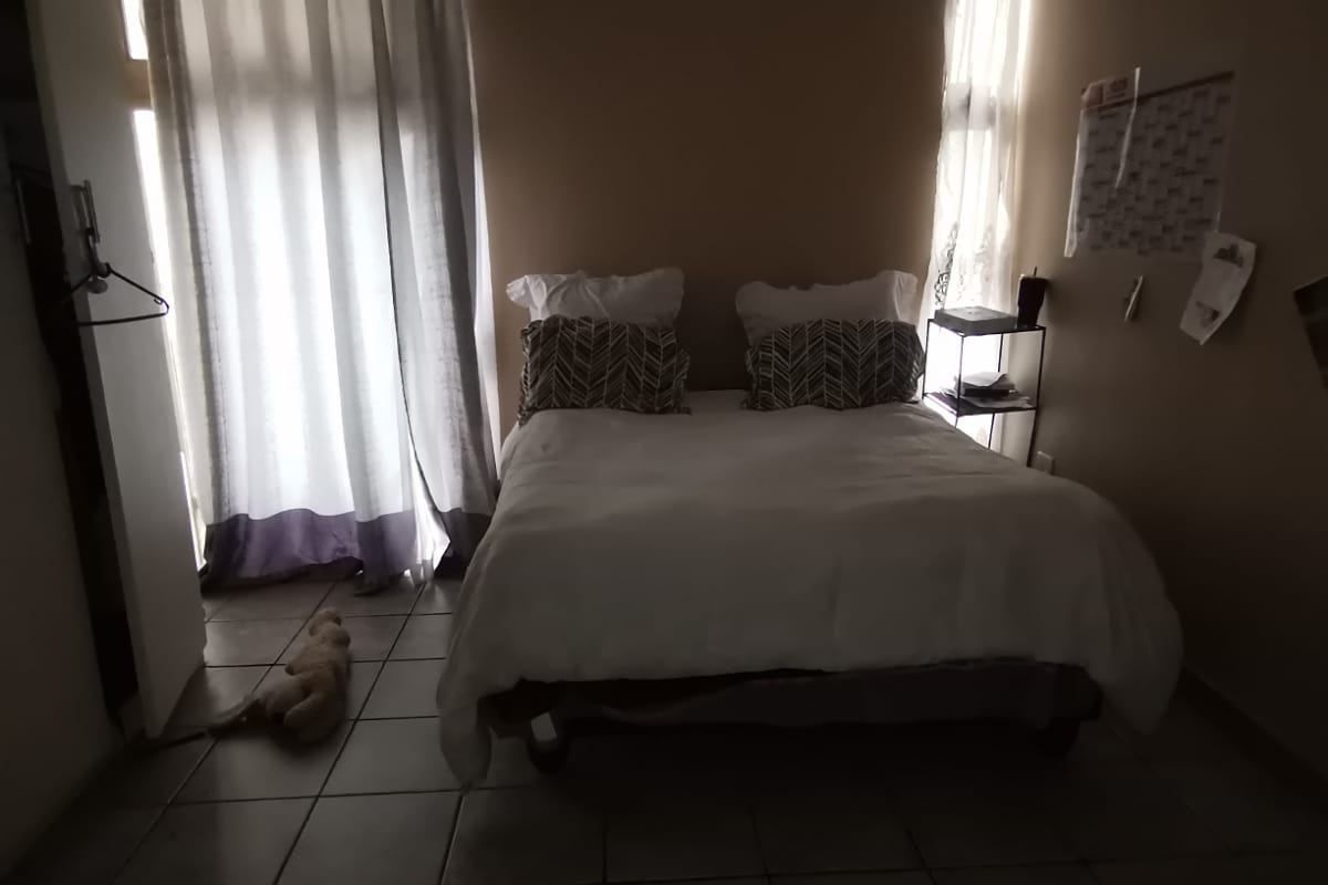 A bedroom featuring tiled flooring and dual windows with curtains, providing natural light to the space.