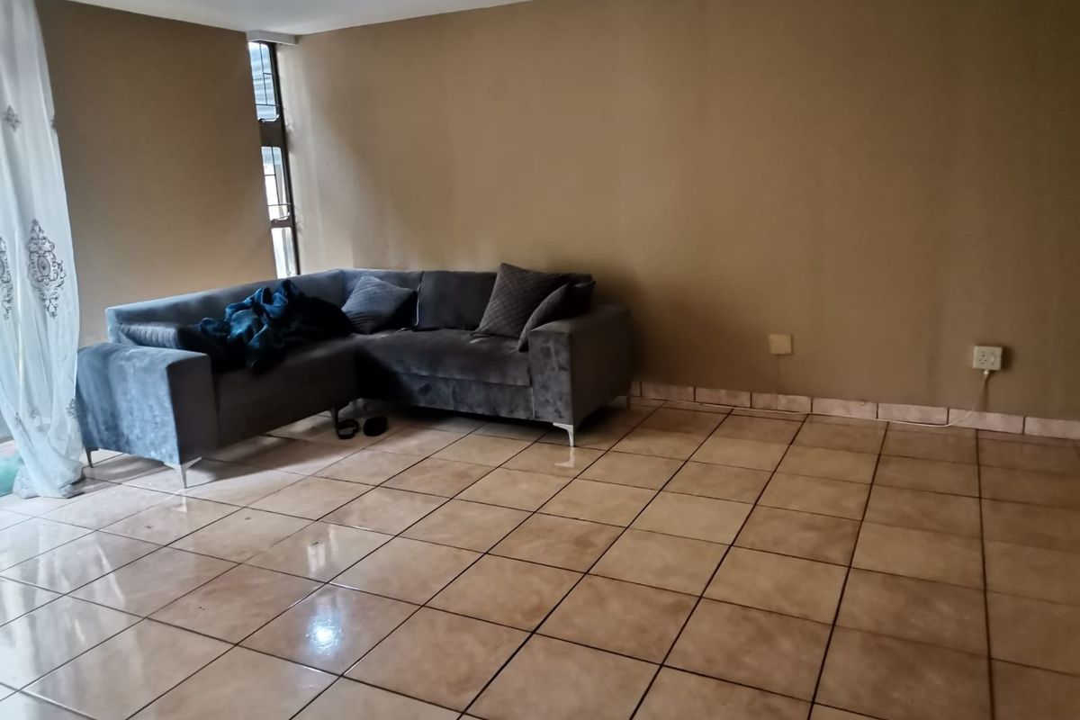 A spacious living area featuring neutral wall tones and tiled flooring, offering a versatile layout for comfortable seating and relaxation.