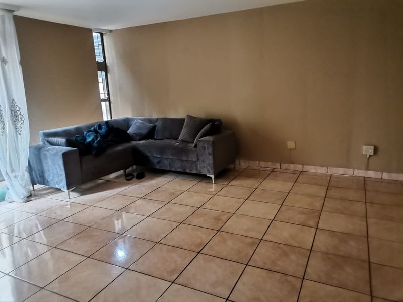 A spacious living area featuring neutral wall tones and tiled flooring, offering a versatile layout for comfortable seating and relaxation.