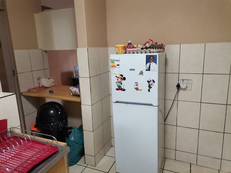 A functional kitchen area featuring tiled walls, a built-in counter space, and dedicated appliance placement.