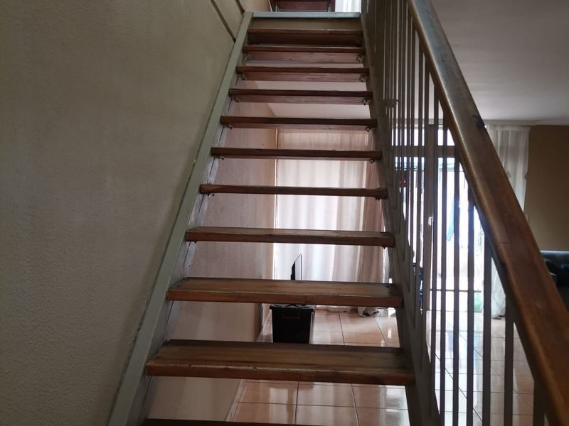 A staircase with wooden treads and a metal railing connecting levels within the apartment.