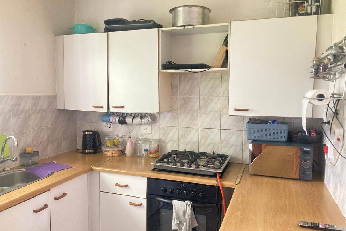 A compact kitchen featuring laminate countertops, built-in cabinetry, a gas hob, and an integrated oven, requiring cosmetic updates to modernize the space.