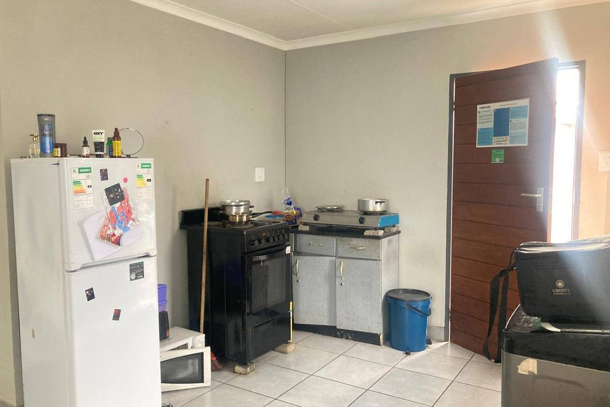 A functional kitchen area featuring tiled flooring, basic cabinetry, and a freestanding stove, offering potential for modernization and improved layout.