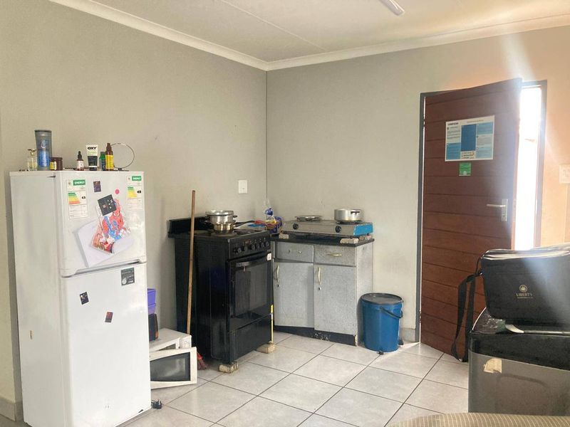A functional kitchen area featuring tiled flooring, basic cabinetry, and a freestanding stove, offering potential for modernization and improved layout.