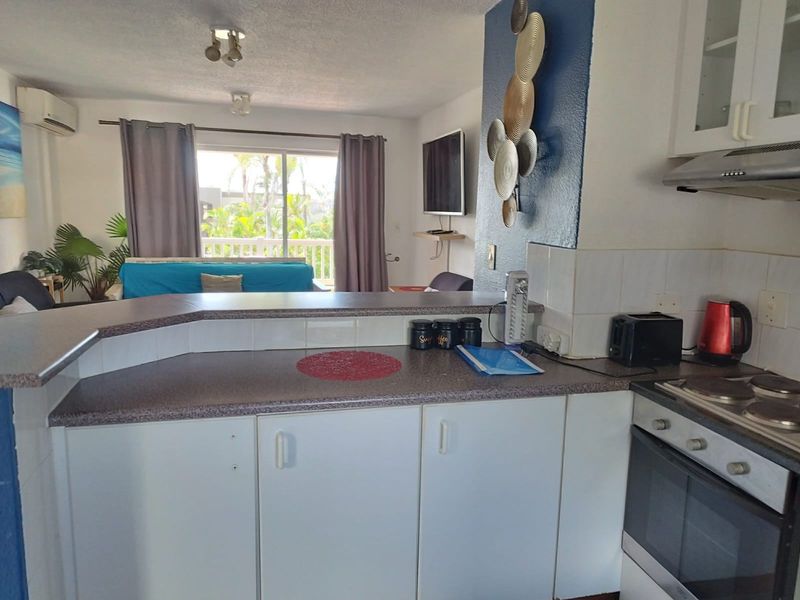 Open-plan kitchen and living area featuring a breakfast bar, built-in oven, and sliding door access to a balcony.