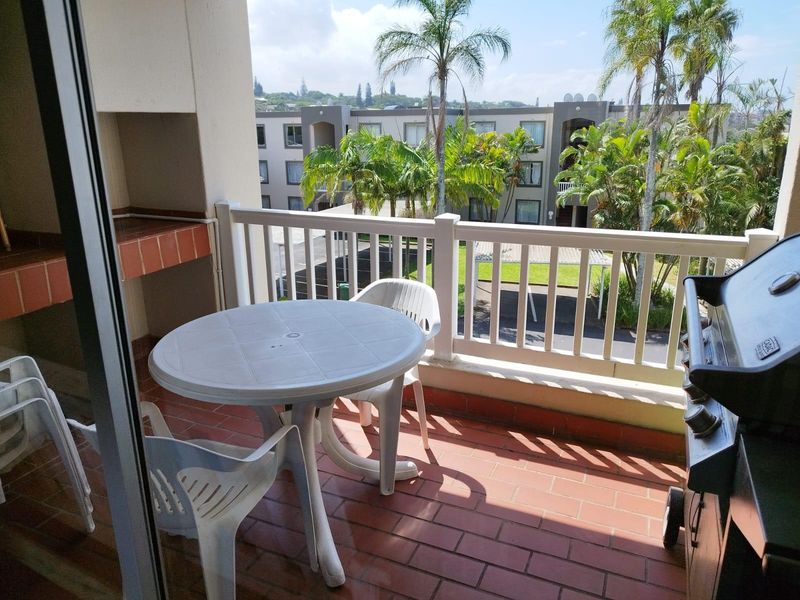 Covered balcony featuring a built-in brick braai, tiled flooring, and a railing, offering an outdoor space for relaxation and entertaining.