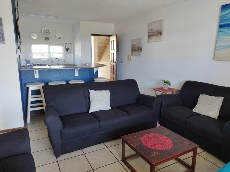Open plan living area featuring a breakfast bar, kitchen sink, and tiled flooring, providing a functional and connected space.