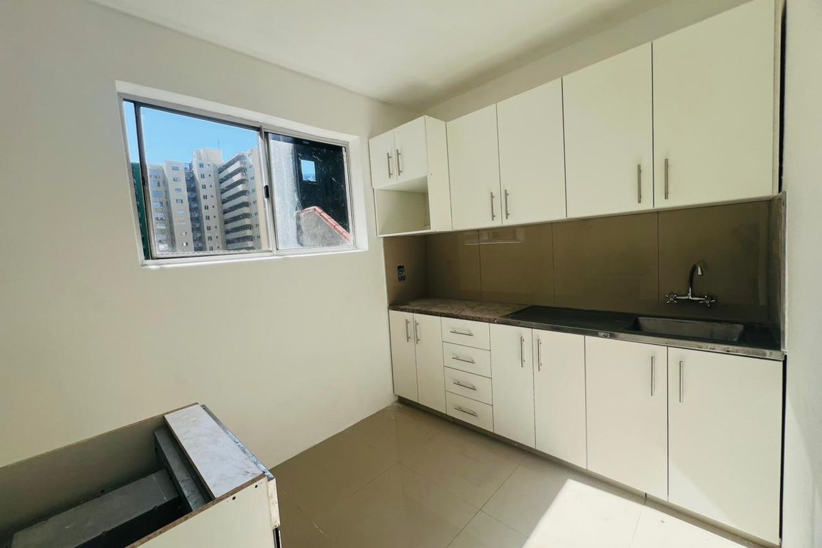 A compact kitchen featuring white cabinetry, a stainless steel sink, and tiled flooring, offering a clean and functional space ready for appliance installation.