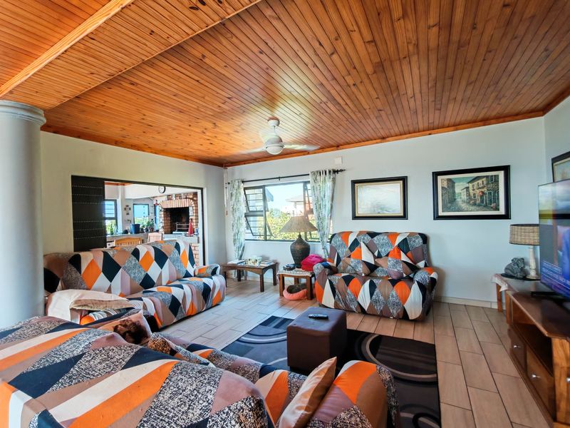 Spacious living room featuring a warm timber tongue and groove ceiling, tiled flooring, and a ceiling fan, with an open flow to the adjacent area.