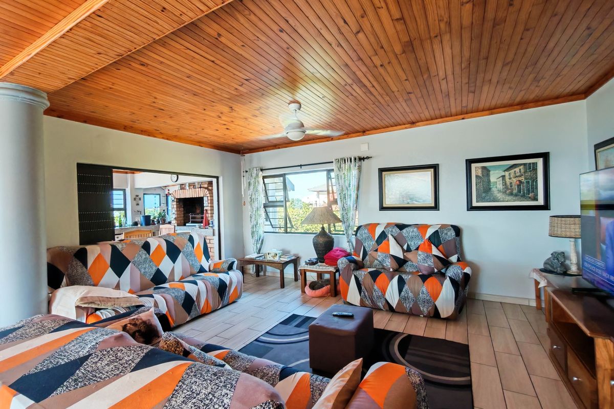 Spacious living room featuring a warm timber tongue and groove ceiling, tiled flooring, and a ceiling fan, with an open flow to the adjacent area.