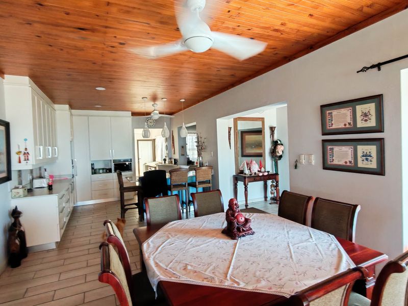 Open plan living and kitchen area featuring a warm timber ceiling, tiled floors, and modern white cabinetry with integrated lighting.