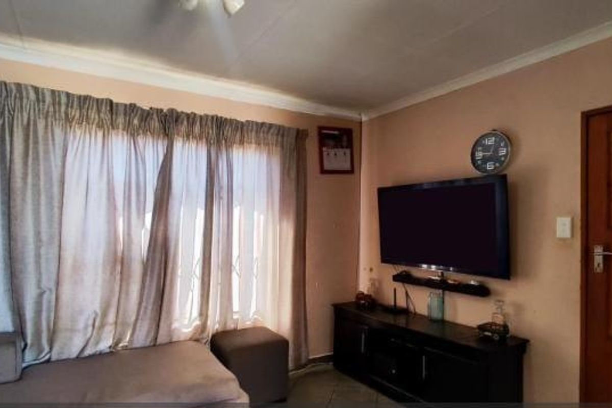 A living room featuring a timber door, security gate, and curtain rails, providing a functional and lived-in space.