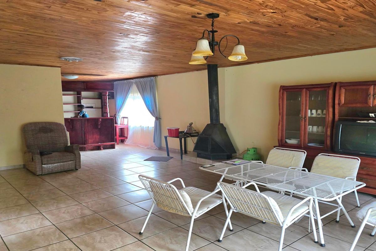 Spacious living area featuring a wood-paneled ceiling, tiled floors, a built-in bar, and a central freestanding fireplace.