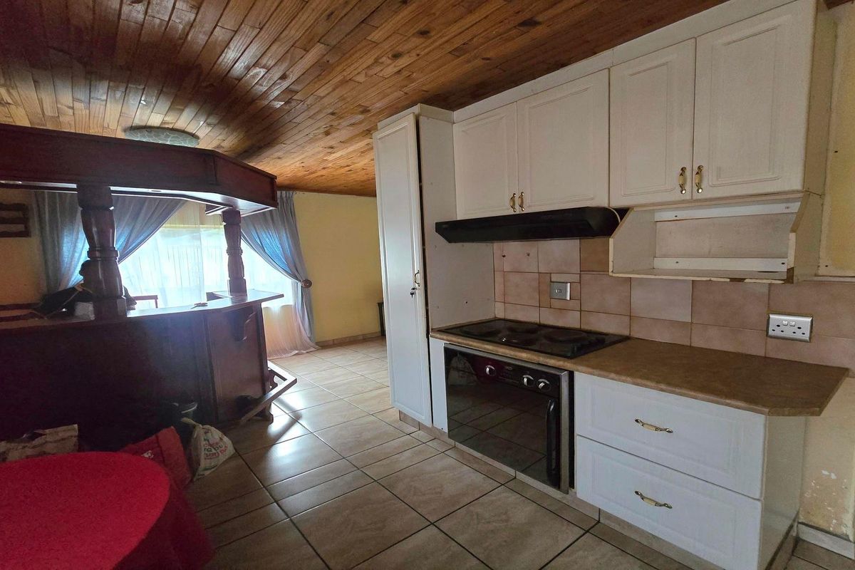 Kitchen area featuring white cabinetry, built-in oven and hob, tiled splashback, and a distinctive timber-clad ceiling.