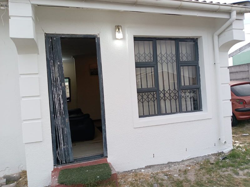 Front exterior view of the property featuring a security gate, window security bars, and external lighting.