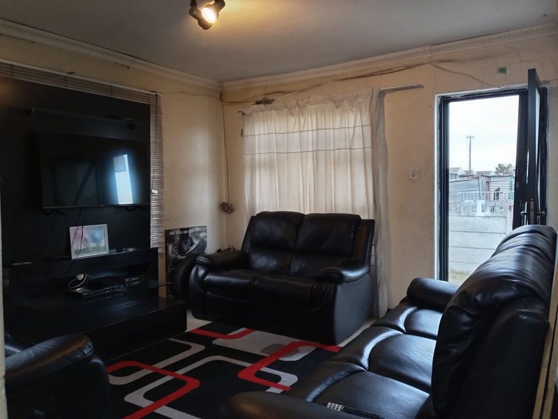 A living room featuring a built-in media unit, ceiling cornice, and sliding door access to the exterior, showing signs of wear and maintenance needs.
