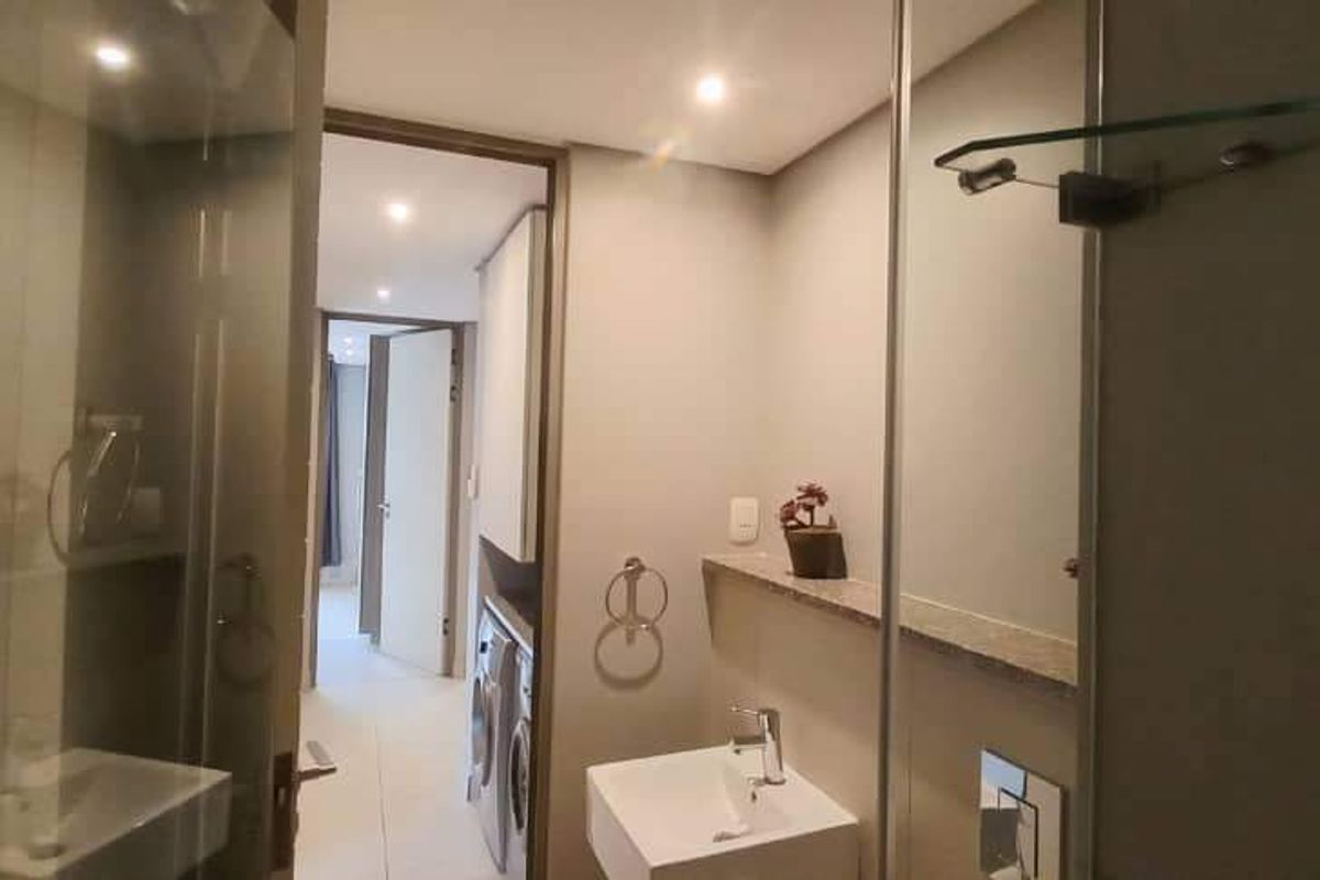 Modern bathroom featuring a wall-mounted basin, stone vanity shelf, and a glass-enclosed shower, with clean finishes and recessed lighting.