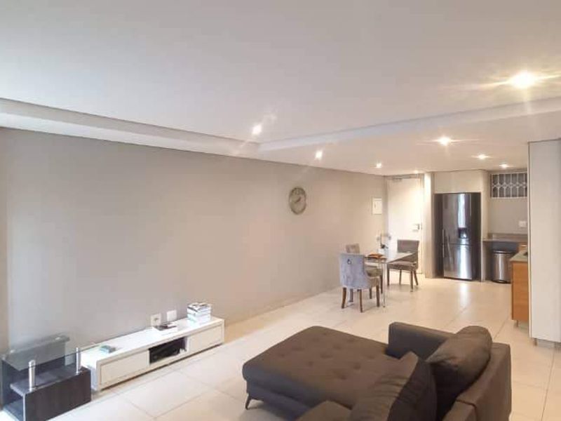 Spacious open-plan living and dining area featuring neutral tones, tiled flooring, recessed lighting, and a modern bulkhead ceiling design.