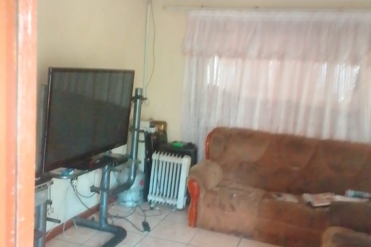 A living room area featuring tiled flooring and curtain rails, requiring cosmetic updates to improve the overall aesthetic and condition of the space.