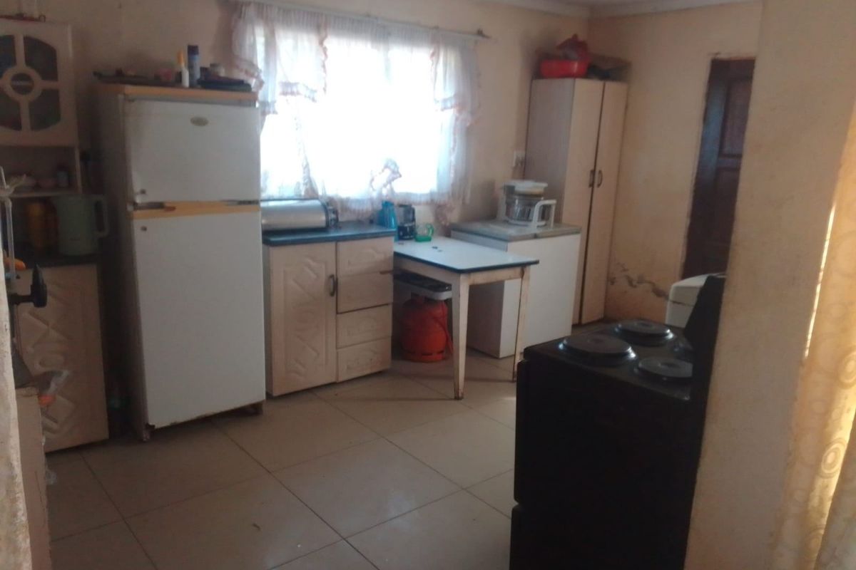 A functional kitchen space featuring tiled flooring and built-in cabinetry, currently showing signs of wear and requiring cosmetic updates.