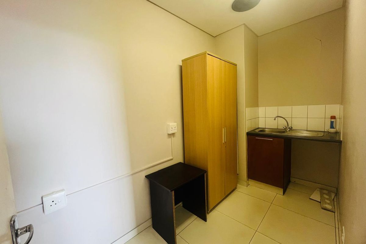 A compact kitchenette area featuring a single sink, tiled splashback, and base cabinetry, suitable for a small office or utility space.