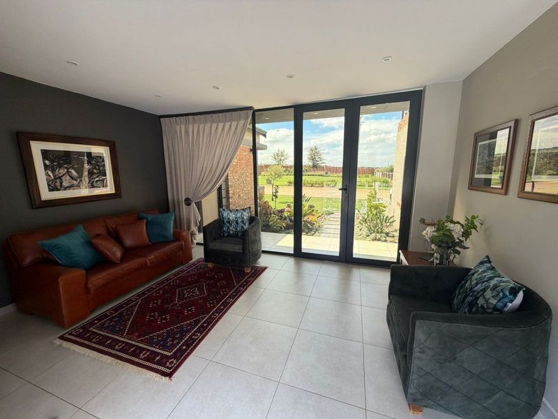 A bright living room featuring large aluminium sliding doors that provide seamless access to the garden and patio area.