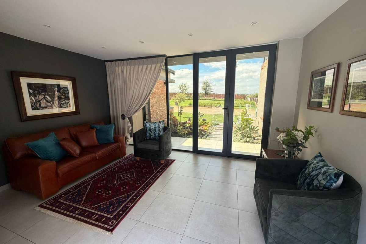A bright living room featuring large aluminium sliding doors that provide seamless access to the garden and patio area.