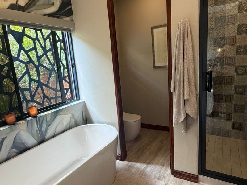 Modern bathroom featuring a sleek freestanding bathtub, a separate walk-in shower with decorative tiling, and a private toilet area.