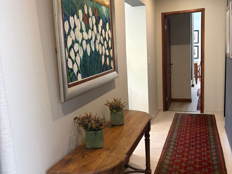 A well-maintained hallway featuring neutral wall tones, tiled flooring, and recessed downlighting, providing a clean transition between living spaces.