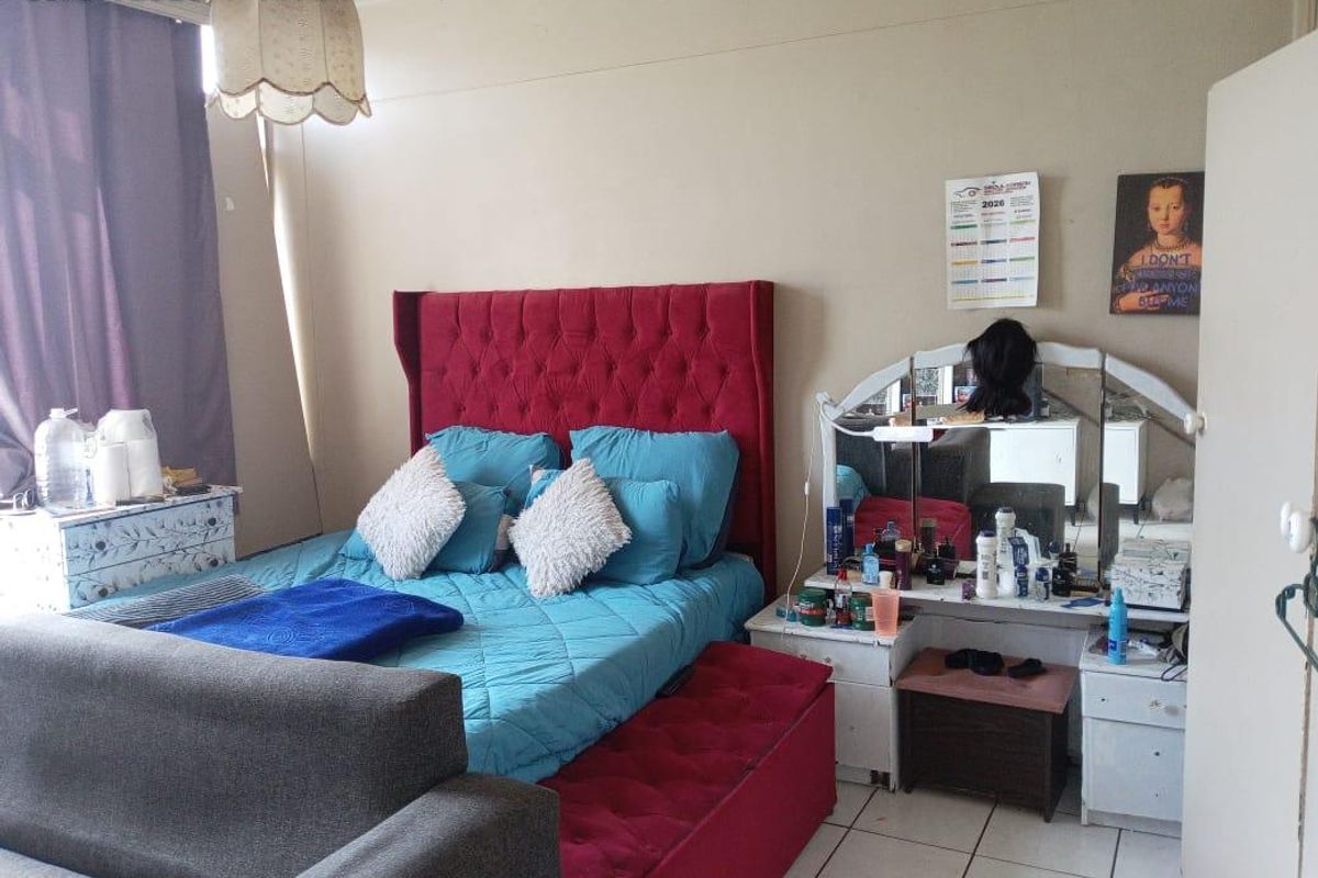 A bedroom featuring tiled flooring and neutral wall finishes, providing a functional space for rest.