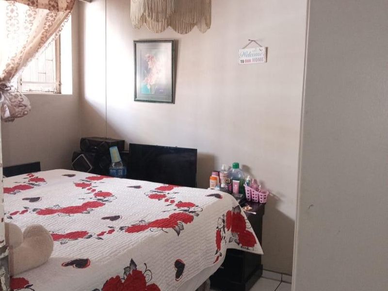 A bedroom featuring tiled flooring and a window with curtain treatments.