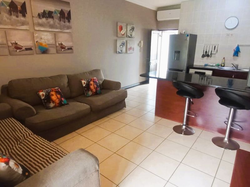 Open-plan living area featuring a kitchen with a breakfast bar, tiled flooring, and direct access to the entrance.