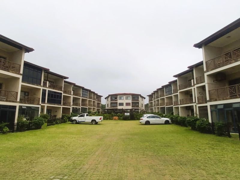 A view of the apartment complex courtyard featuring landscaped lawns, paved pathways, and multi-story residential blocks with private balconies.