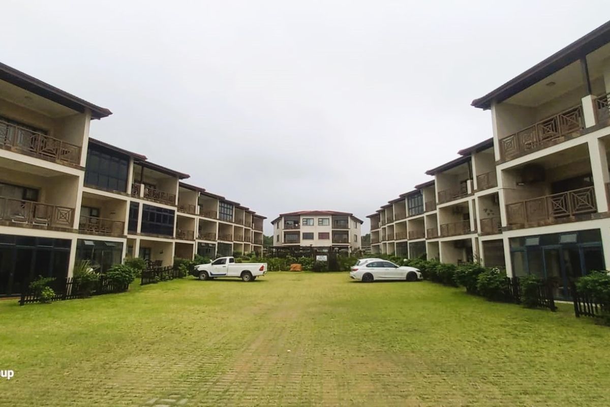 A view of the apartment complex courtyard featuring landscaped lawns, paved pathways, and multi-story residential blocks with private balconies.