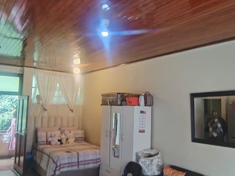 An open-plan living and sleeping area featuring tiled flooring and a timber-paneled ceiling, with direct access to an outdoor space.