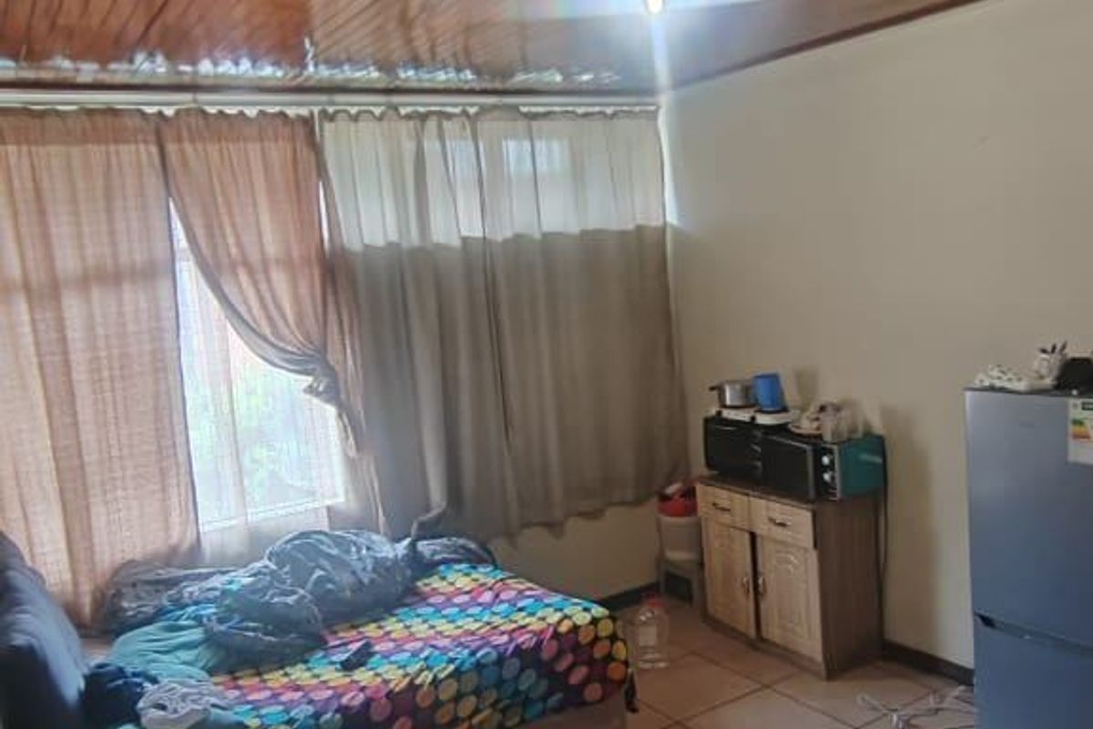 A bedroom featuring a wooden panelled ceiling and tiled flooring, providing a functional living space.