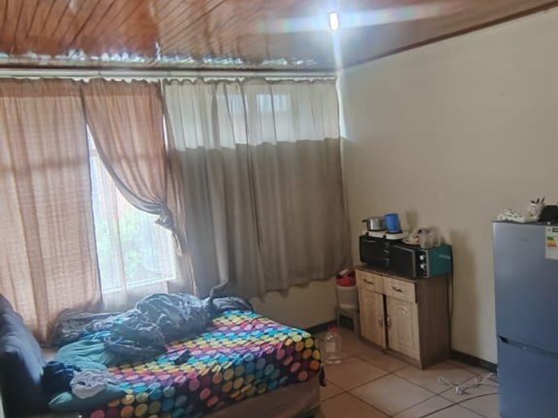 A bedroom featuring a wooden panelled ceiling and tiled flooring, providing a functional living space.