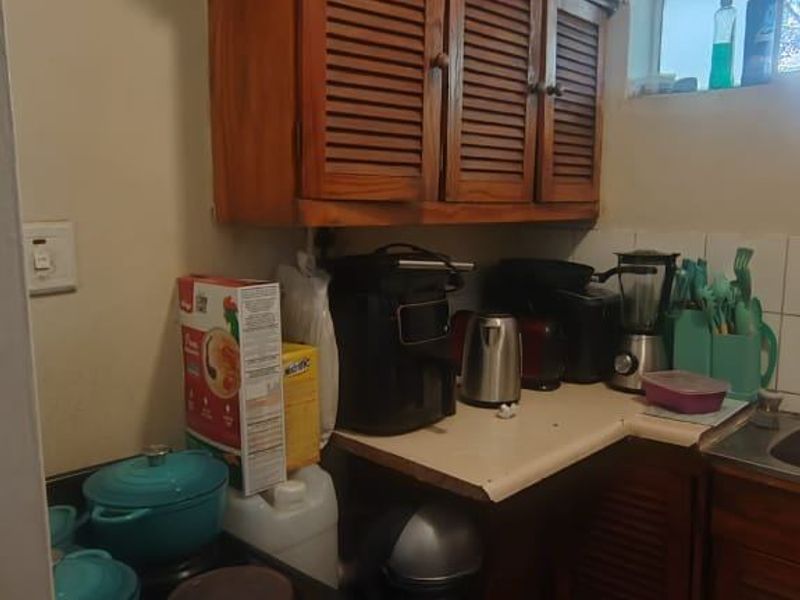 A compact kitchen featuring wooden louvered cabinetry, tiled flooring, and a built-in stove, offering a functional layout with potential for modernization.
