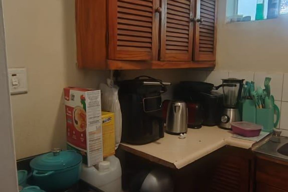 A compact kitchen featuring wooden louvered cabinetry, tiled flooring, and a built-in stove, offering a functional layout with potential for modernization.