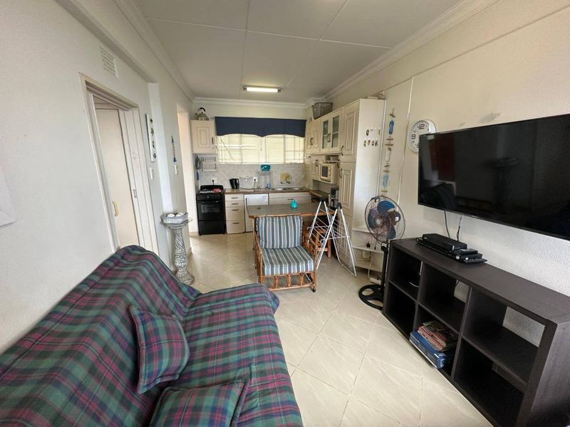 Open-plan living area featuring a compact kitchen with tiled flooring and dated cabinetry, providing a functional layout for apartment living.