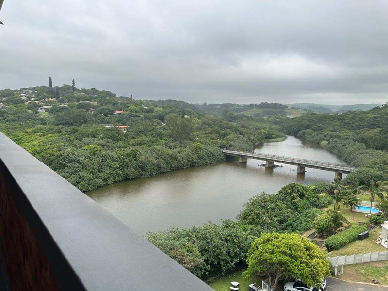 Elevated scenic view overlooking a river, bridge, and lush green landscape from an apartment balcony.