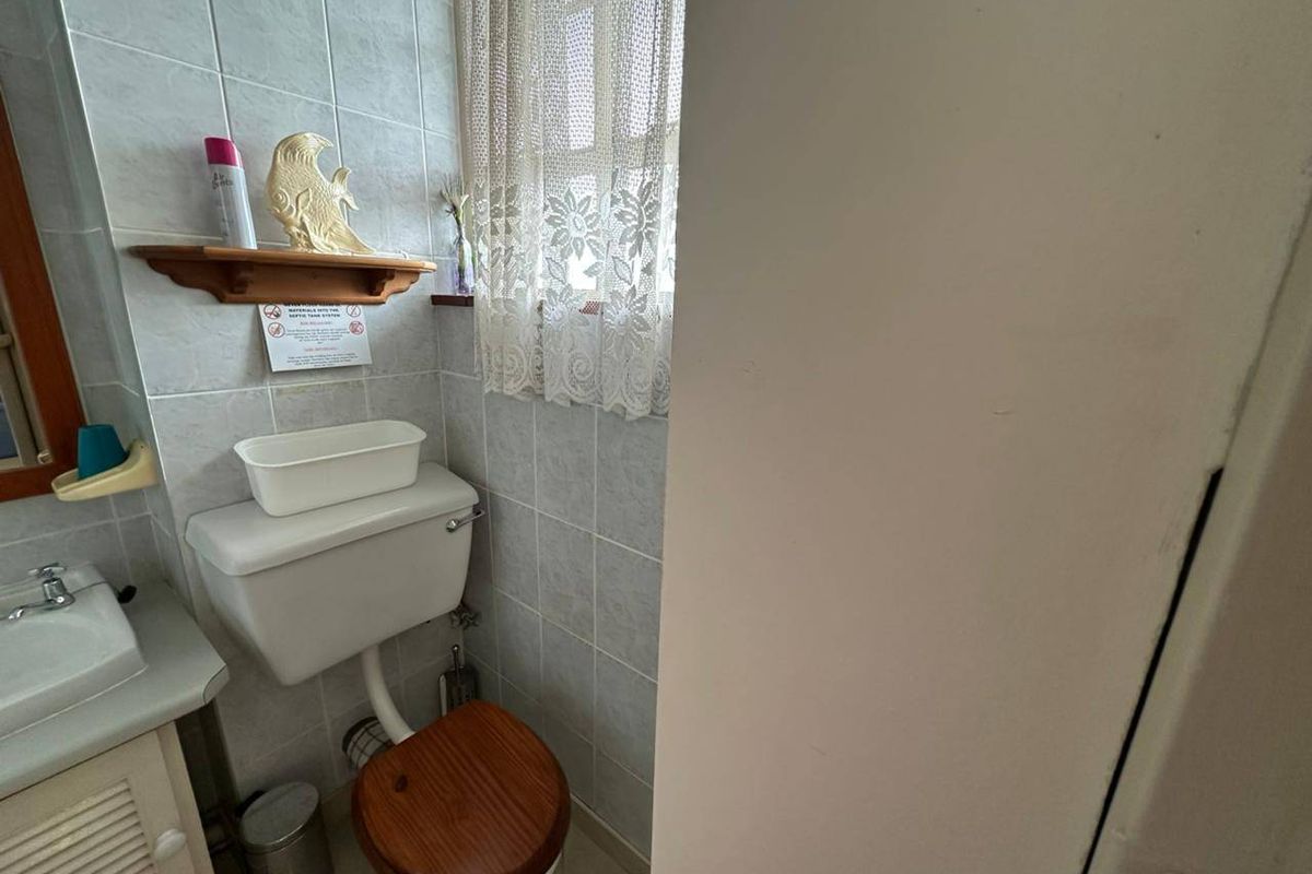 A functional bathroom featuring tiled walls, a vanity cabinet with a basin, and a standard toilet.