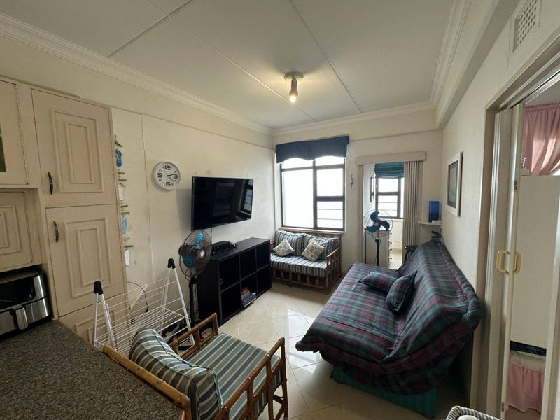 Compact open-plan living area featuring tiled floors, built-in cabinetry, and natural light through aluminium windows.