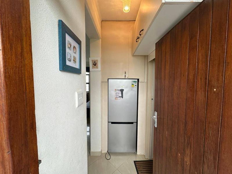 A narrow hallway featuring built-in cabinetry and tiled flooring, providing functional storage space within the apartment.