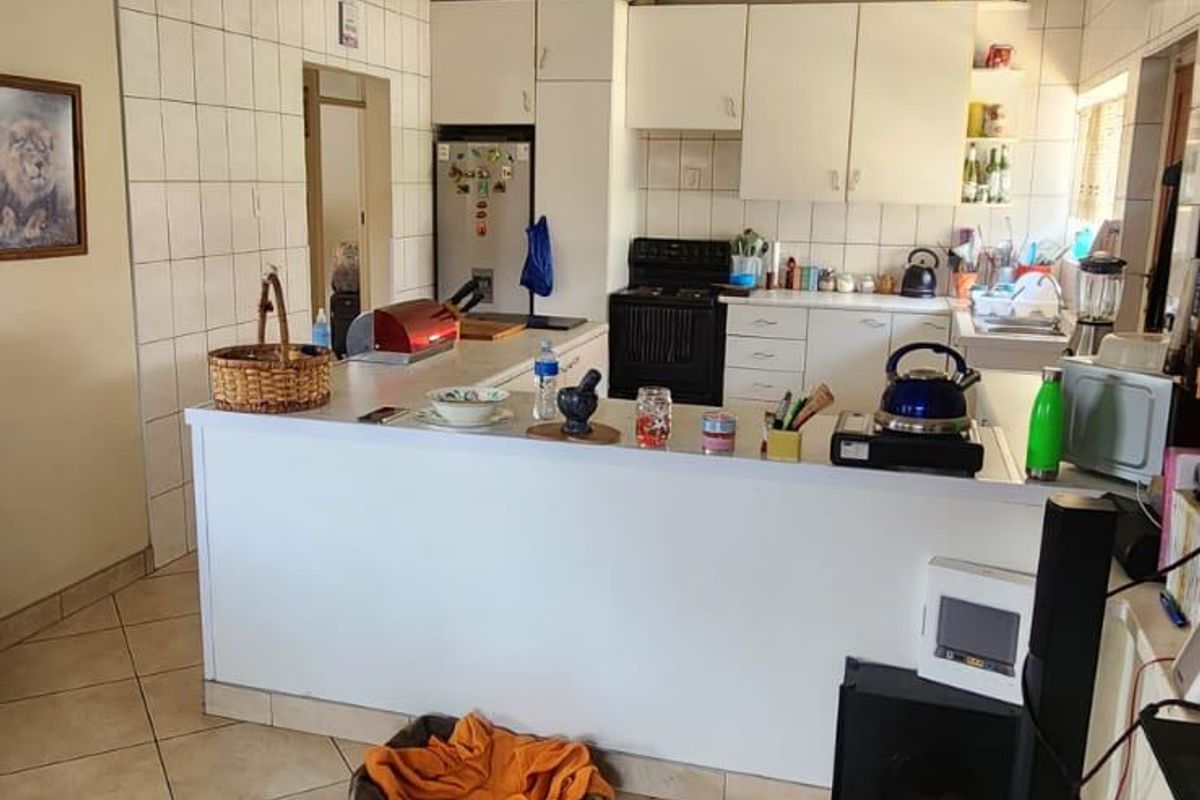 A functional kitchen featuring white cabinetry, tiled flooring, a breakfast bar, and a tiled splashback, offering a practical layout for daily meal preparation.