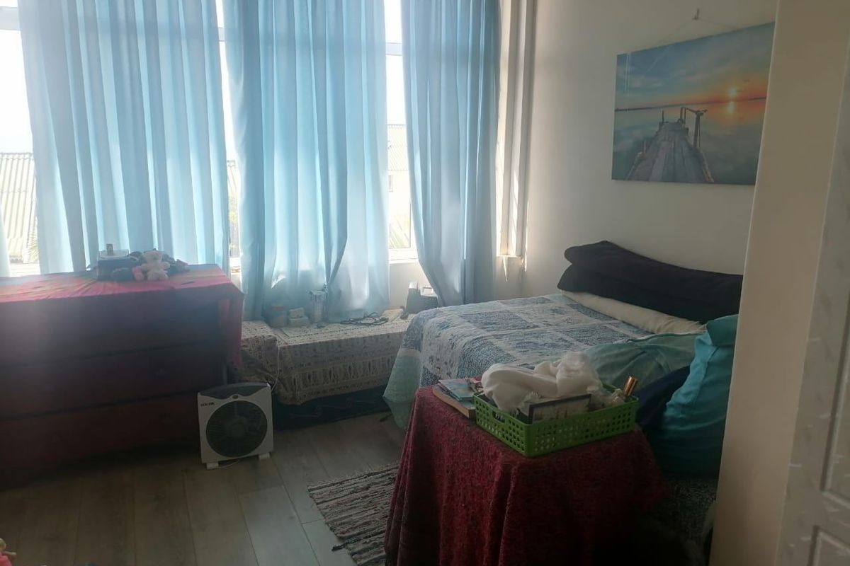 A bedroom featuring laminate flooring and a large window that allows for ample natural light.