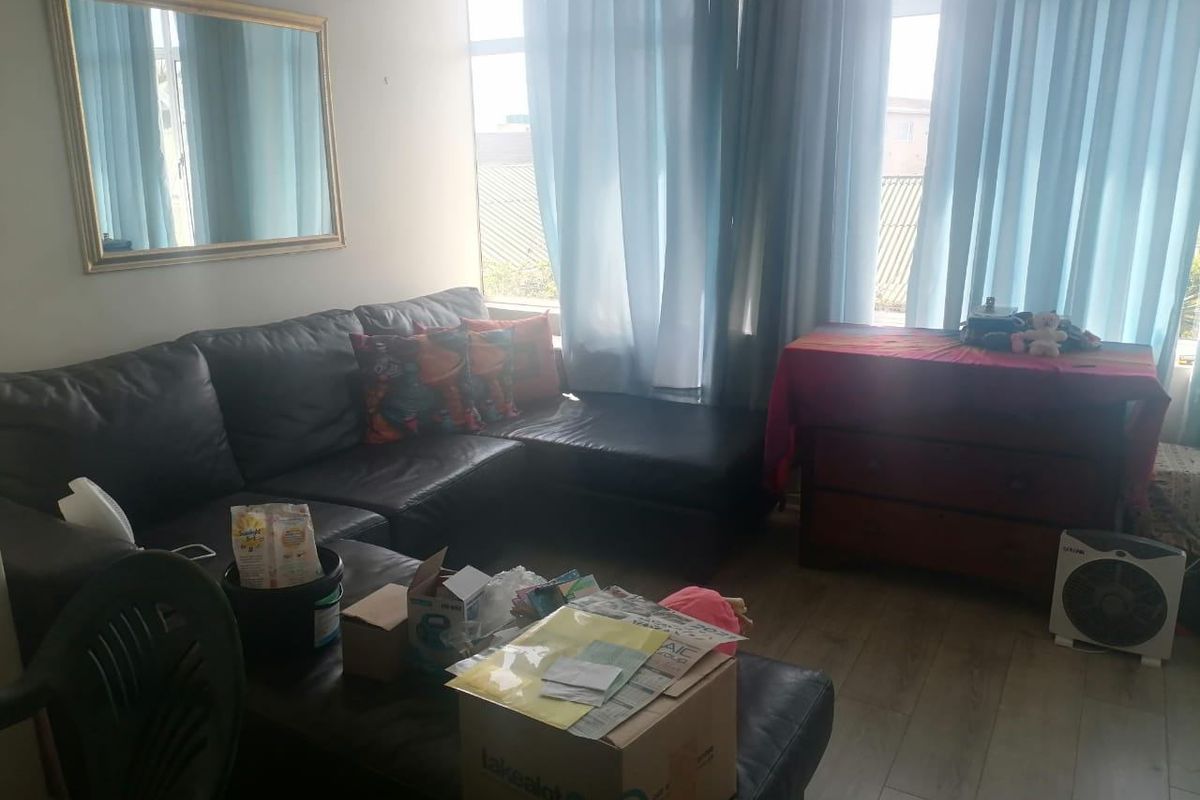 A living room area featuring laminate flooring and large windows that provide natural light.